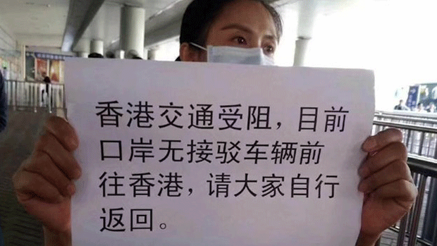 A customs officer in Shenzhen holds a sign warning of disruptions in travel to and from Hong Kong, Nov. 15, 2019.