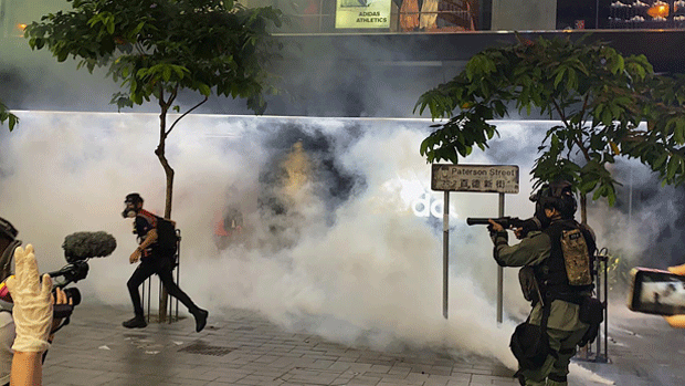 Hong Kong riot police fire tear gas at a fleeing protester in an undated photo.