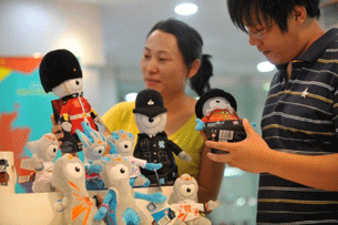 A Chinese customer inspects mascots for the 2012 London Olympics at a shop in Beijing, Aug. 21, 2011.