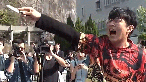 A pro-Beijing protester threatens graduating students with a knife at the Chinese University of Hong Kong, Nov. 7, 2019.