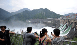 Local residents watch water gushing out from a dam in Jiande city in east China's Zhejiang province, June 21, 2011.