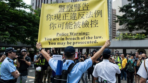 A police officer displays a warning banner during a flash mob rally to show support for pro-democracy protesters in the Central district in Hong Kong, Oct. 11, 2019. 