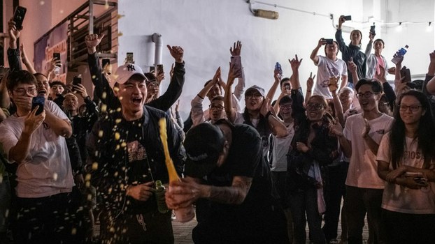 A pro-democracy supporter (C) opens a bottle of champagne outside a polling station to celebrate after pro-Beijing candidate Junius Ho lost a seat in the district council elections in Tuen Mun district of Hong Kong, Nov. 25, 2019. 
