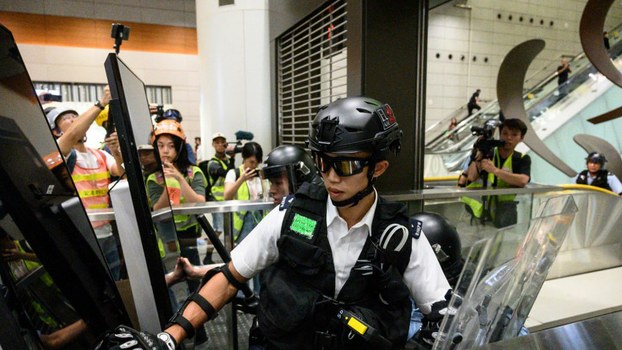 Police officers push through a barricade of vandalized television screens, set up by protesters to block an entrance to the Kowloon MTR station in Hong Kong, Sept. 22, 2019.