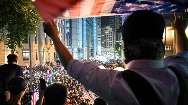 A man waves a US national flag as protesters attend a rally in Hong Kong, calling on US politicians to pass a bill that could alter Washington's relationship with the trading hub, Oct. 14, 2019