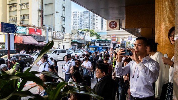 Bystanders stand behind a cordon set by police near the site where a pro-democracy protester was shot by a policeman in the Sai Wan Ho area of Hong Kong, Nov. 11, 2019.
