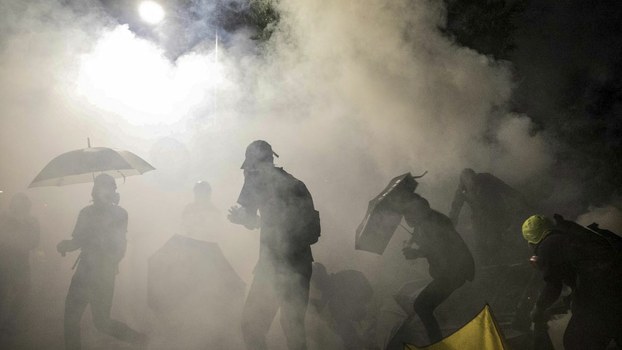 Protesters react to tear gas canister during clashes with police at the Chinese University of Hong Kong (CUHK) in Hong Kong, Nov. 12, 2019.