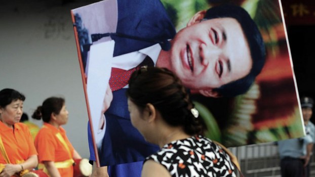 A Chinese woman carries a portrait of Chongqing Communist Party chief Bo Xilai after one of the city's Maoist "red" culture sessions where workers gather to sing revolutionary songs, in 2011 file photo.