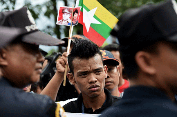Myanmar migrant workers hold national flags as they wait for the arrival of State Counselor and Foreign Minister Aung San Suu Kyi at a market in Samut Sakhon province, west of Bangkok, Thailand, on June 23, 2016.